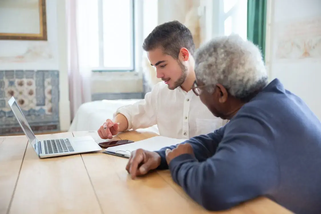 An insurance agent showing an elderly man how much plan G will cost him.